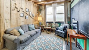 A cozy room with a wooden ceiling, a blackboard, a grey sofa, and a patterned rug. - 'old School ATV Retreat' On Warrior Trail, 8BR (Gary)