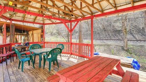 A covered outdoor area with a picnic table and chairs, wooden deck, and a view of a wooded area. - 'old School ATV Retreat' On Warrior Trail, 8BR (Gary)