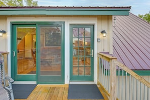 A building with a green door, a wooden deck, and a metal roof.