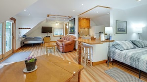 Een moderne loftkamer met een eethoek, een zithoek, een keuken en een groot raam.
