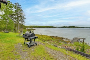 A lakeside view with a grill and dock.
