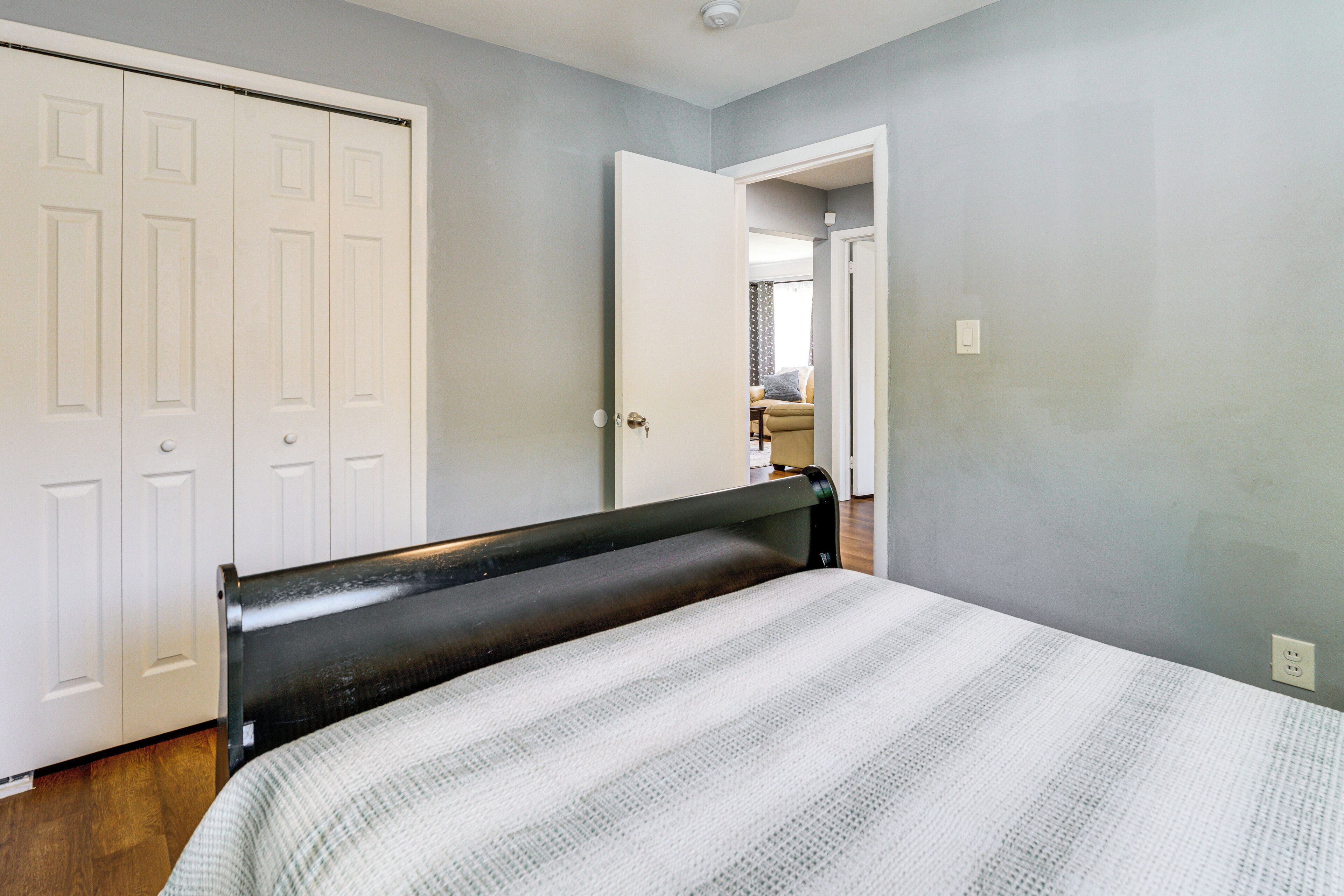 Une chambre à coucher comprenant un lit, une armoire et une porte donnant sur une autre pièce.