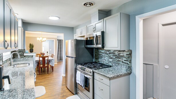 Una cocina con encimeras de granito, electrodomésticos de acero inoxidable y una zona de comedor con mesa y sillas.