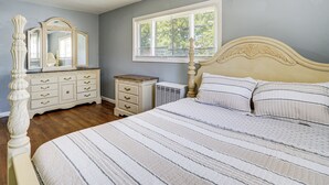 Un dormitorio con cama, cómoda, espejo y ventana.