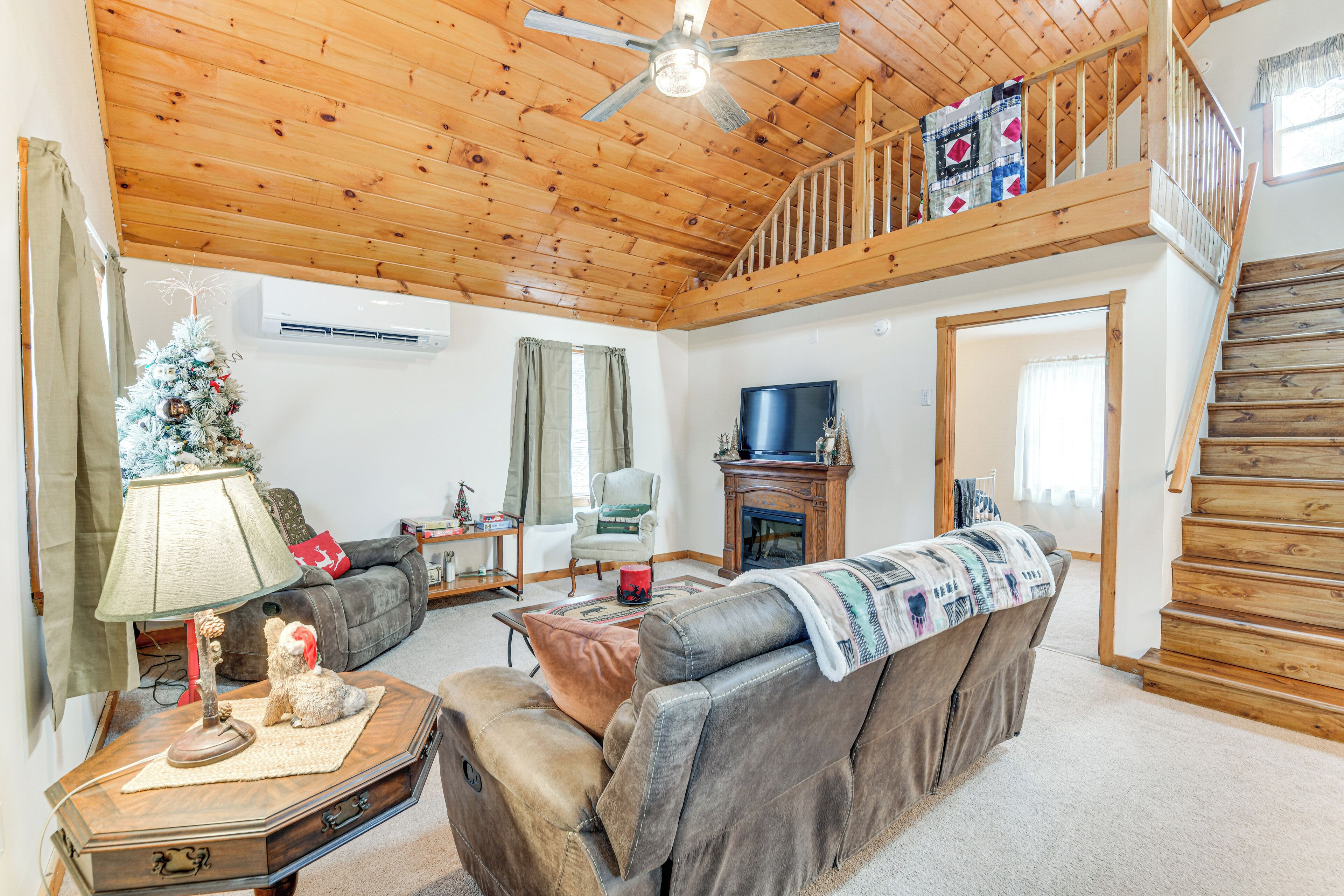 A cozy living room with a fireplace, a television, and a staircase leading to an upper level.
