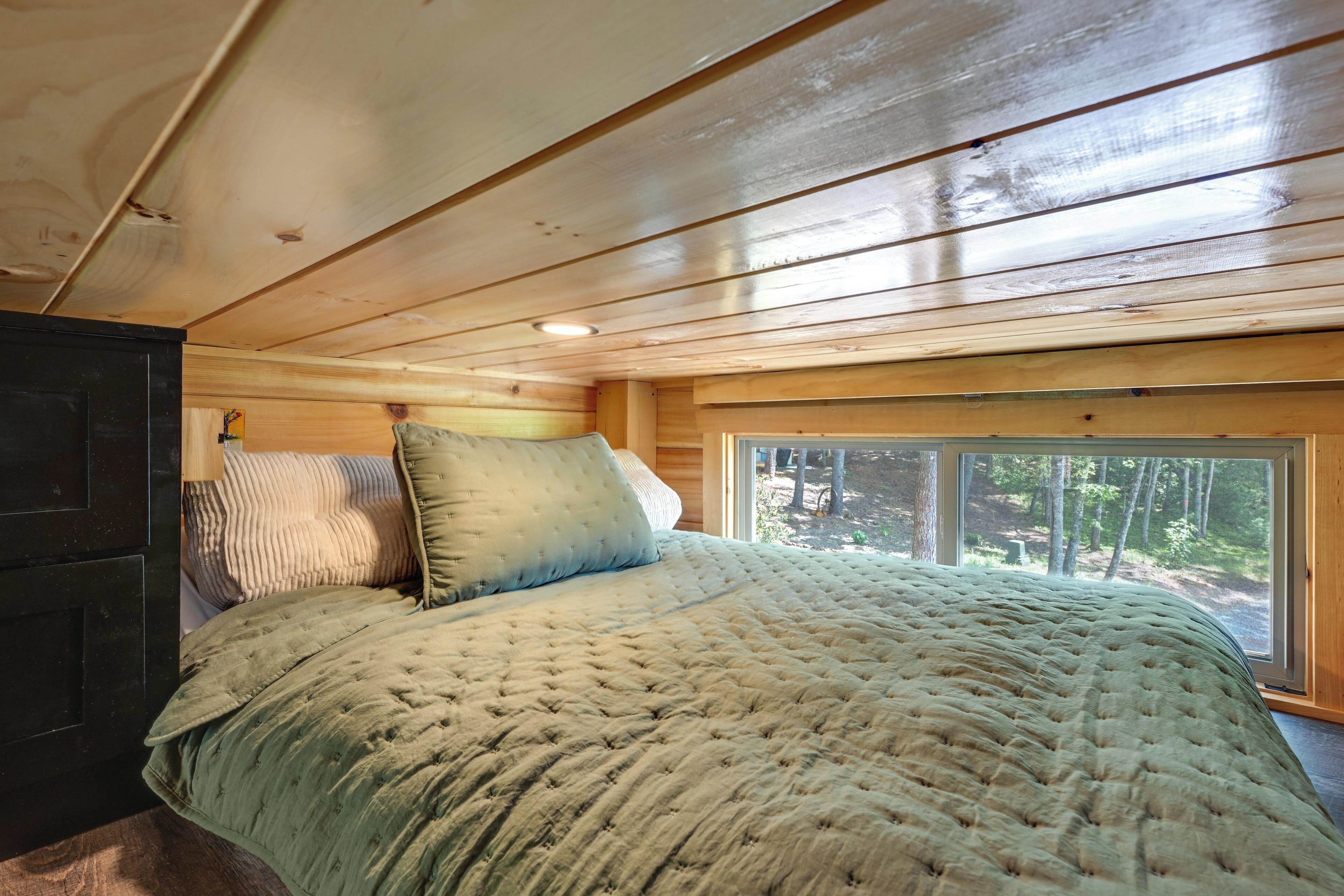 A bedroom with a bed, pillows, a window, and a view of the outdoors.