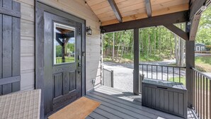 A wooden porch with a door, a bench, and a small covered area with a bench.