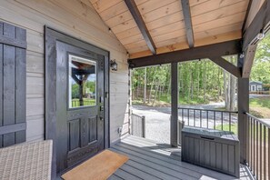 Une véranda en bois avec une porte, un banc et un petit espace abrité également équipé d’un banc.