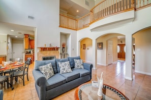A spacious living area with a dark grey sofa, a dining table with chairs, and a kitchen in the background. - Red Oak Group Getaway w/ Yard + Patio (Red Oak)