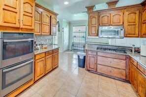 A kitchen with wooden cabinets, stainless steel appliances, and a tiled floor. - Red Oak Group Getaway w/ Yard + Patio (Red Oak)