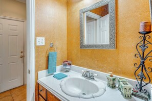 A bathroom with a white sink, a mirror with an ornate frame, a towel rack, and a decorative candle holder. - Red Oak Group Getaway w/ Yard + Patio (Red Oak)
