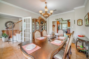 A dining room with a large wooden table set for six, surrounded by chairs, a chandelier, and a mirror. - Red Oak Group Getaway w/ Yard + Patio (Red Oak)