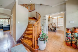 A spacious living area with a wooden staircase, a large potted plant, and decorative vases. - Red Oak Group Getaway w/ Yard + Patio (Red Oak)