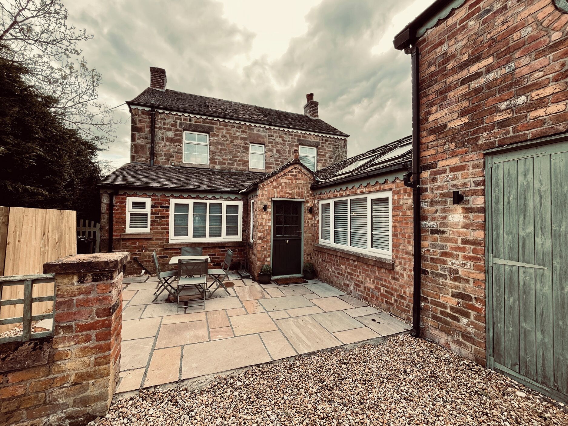 A two-story brick house with a patio, a door, and a window.