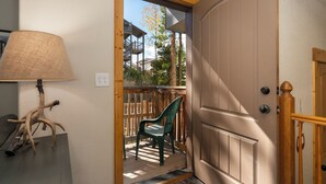 Une porte en bois avec un panneau de verre, une chaise verte à l’extérieur et une lampe sur la gauche.