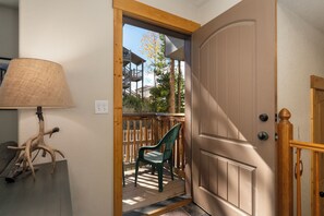 Eine Holztür mit Fensterglas, ein grüner Stuhl davor und eine Lampe auf der linken Seite.