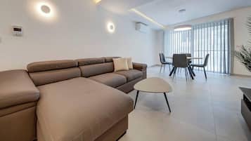 Una sala de estar moderna con un sofá modular, una mesita redonda y un comedor con sillas.