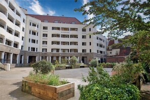 A multi-story building with balconies, a courtyard with planters, and a red-tiled roof. - Bright Duplex Flat in the Desired Area of Euston (London)