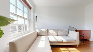 A room with a white sofa, a chair, a plant, and a window. - Bright Duplex Flat in the Desired Area of Euston (London)