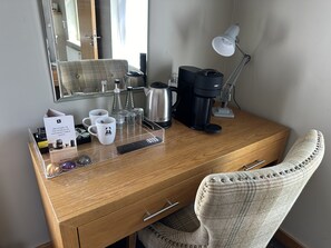 Ein Holztisch mit Kaffeemaschine, Fernbedienung und Lampe.