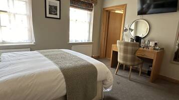 Une chambre d’hôtel avec un lit, un bureau, une chaise, une télévision et une fenêtre avec des rideaux.