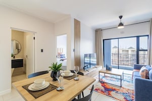 Una sala de estar moderna con comedor, ventanas amplias y vistas a edificios.