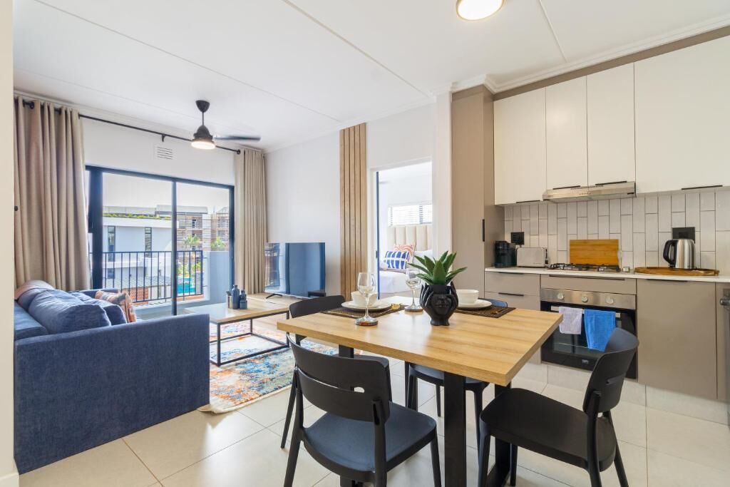 Un apartamento moderno con comedor, cocina y sala de estar con sofá y televisor.