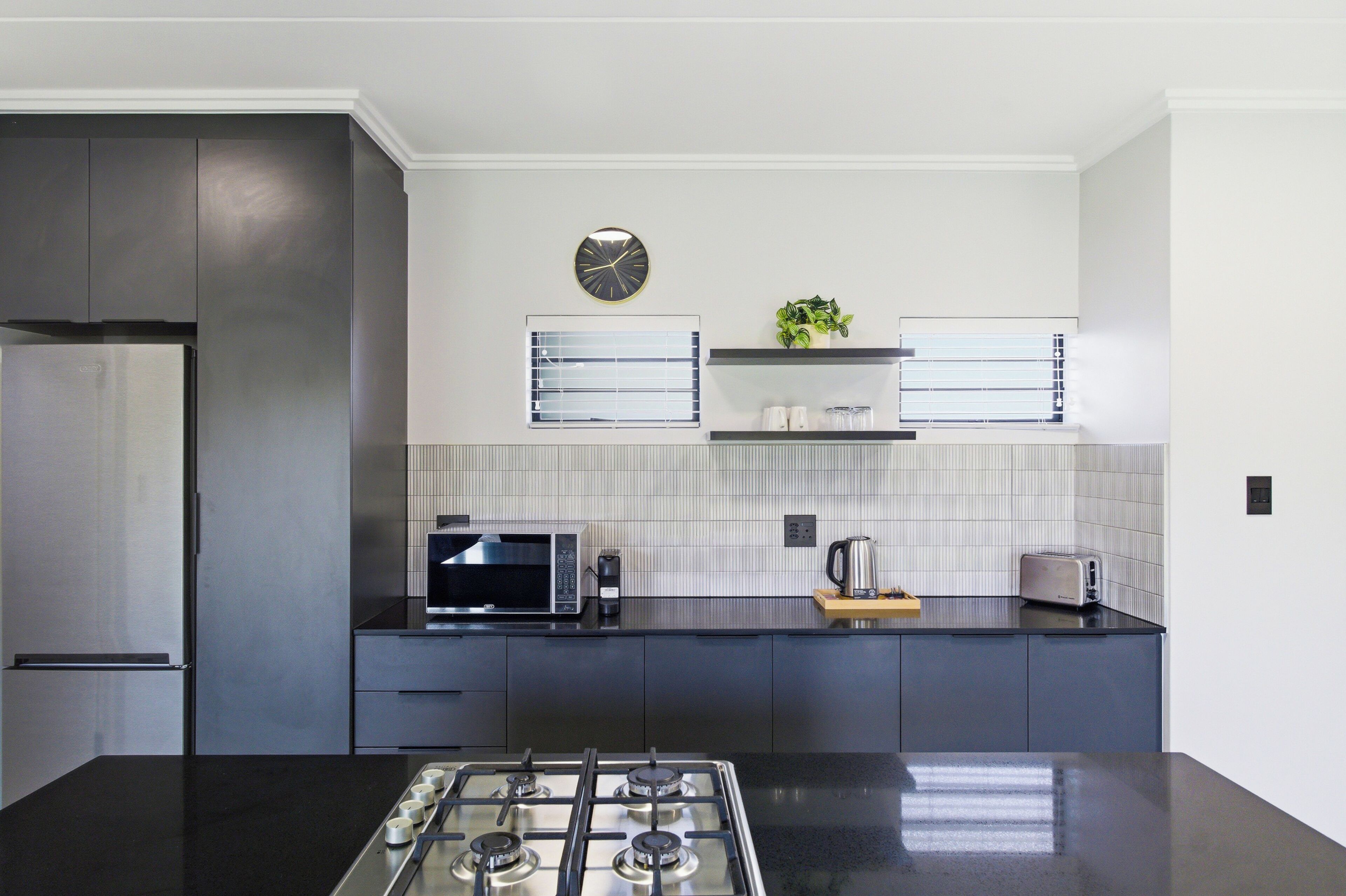A modern kitchen with a gas stove, a microwave, and a refrigerator.