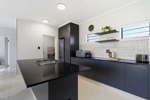 Una cocina moderna con encimeras negras, microondas integrado, cafetera y tostadora.