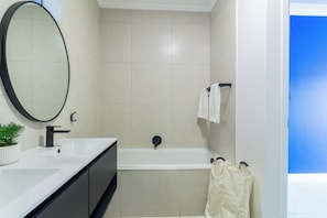 A modern bathroom with a bathtub, a large mirror, and a sink. - Ballito Life Estate (Ballito)