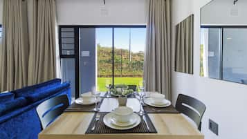 A dining area with a table set for four, a blue sofa, and a view of a garden through a large window.