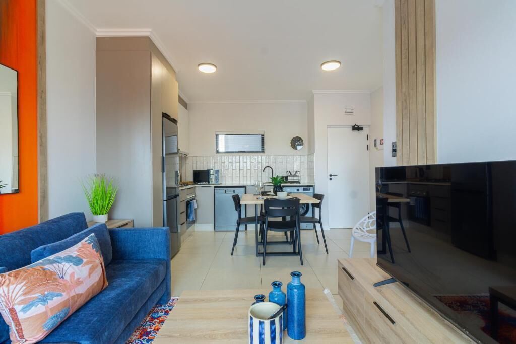 A modern apartment with a living room, dining area, kitchen, and a TV.