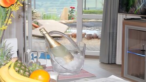 A room with a view of the beach, a table with a bottle of champagne, fruits, and a glass. - Studio with Volcano View at Maarberg Resort in Schalkenmehren by the Lake (Schalkenmehren)