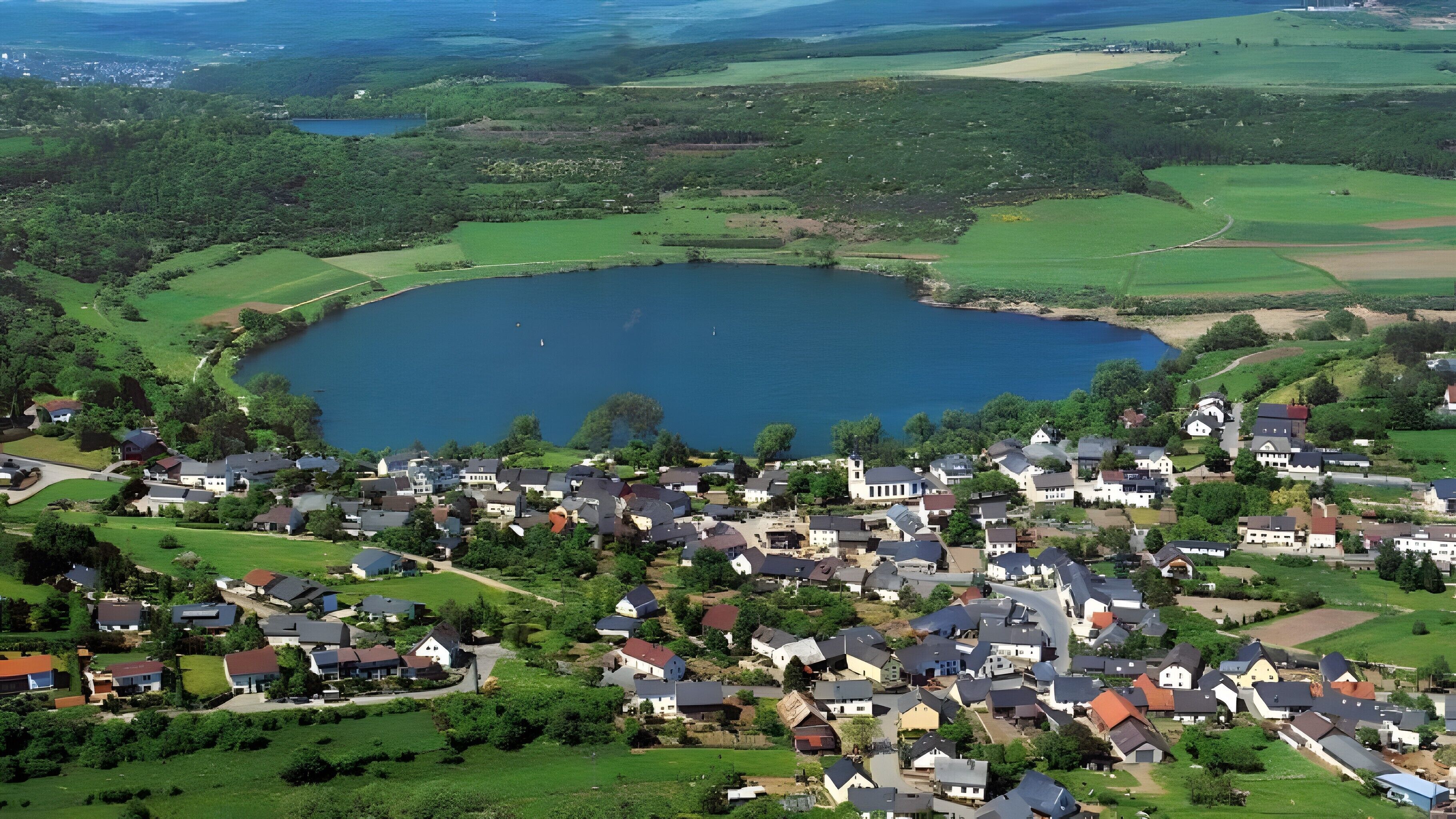 Una zona residenziale sul lago, con case, un'ampia distesa d'acqua e vegetazione circostante.