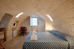 A room with a stone ceiling, a bed with patterned bedding, a chair, a small desk, and a window. - Alloro Double Room in Elegant Villa near Beaches and Countryside (Macchia al Monte)