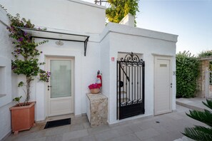 A white building with a glass door, a metal gate, and a fire extinguisher. - Alloro Double Room in Elegant Villa near Beaches and Countryside (Macchia al Monte)