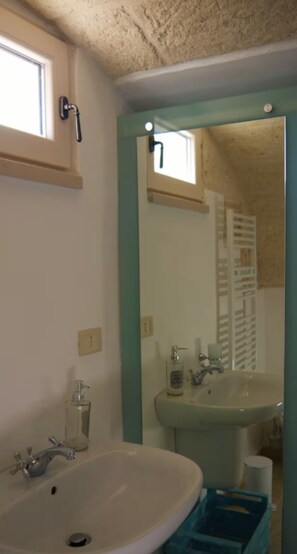 Un baño con lavamanos, espejo y ventana.