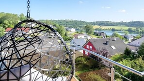 A view from a high vantage point, including a metal structure, a red house, and a lake.