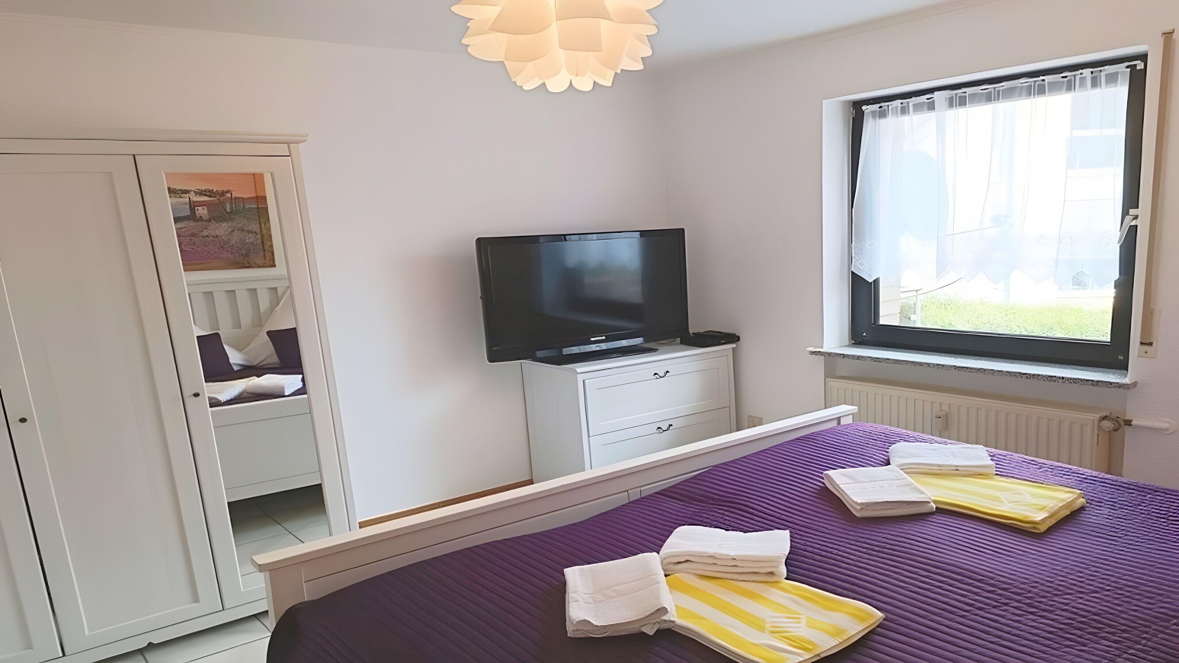 Ein Schlafzimmer mit einem Bett, einem Fernseher, einem Kleiderschrank und einem Fenster mit Blick.