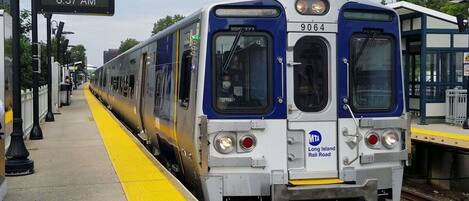 A train at a station platform with a sign indicating 'Flushing 8:37 AM'.