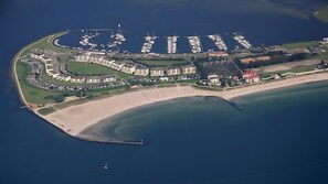 Luftaufnahme einer Küstenregion mit Hafen, Strand und Wohngebäuden.