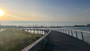 A wooden boardwalk leading to a marina with sailboats.