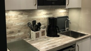 A modern kitchen with a built-in microwave, stainless steel sink, and a coffee maker.