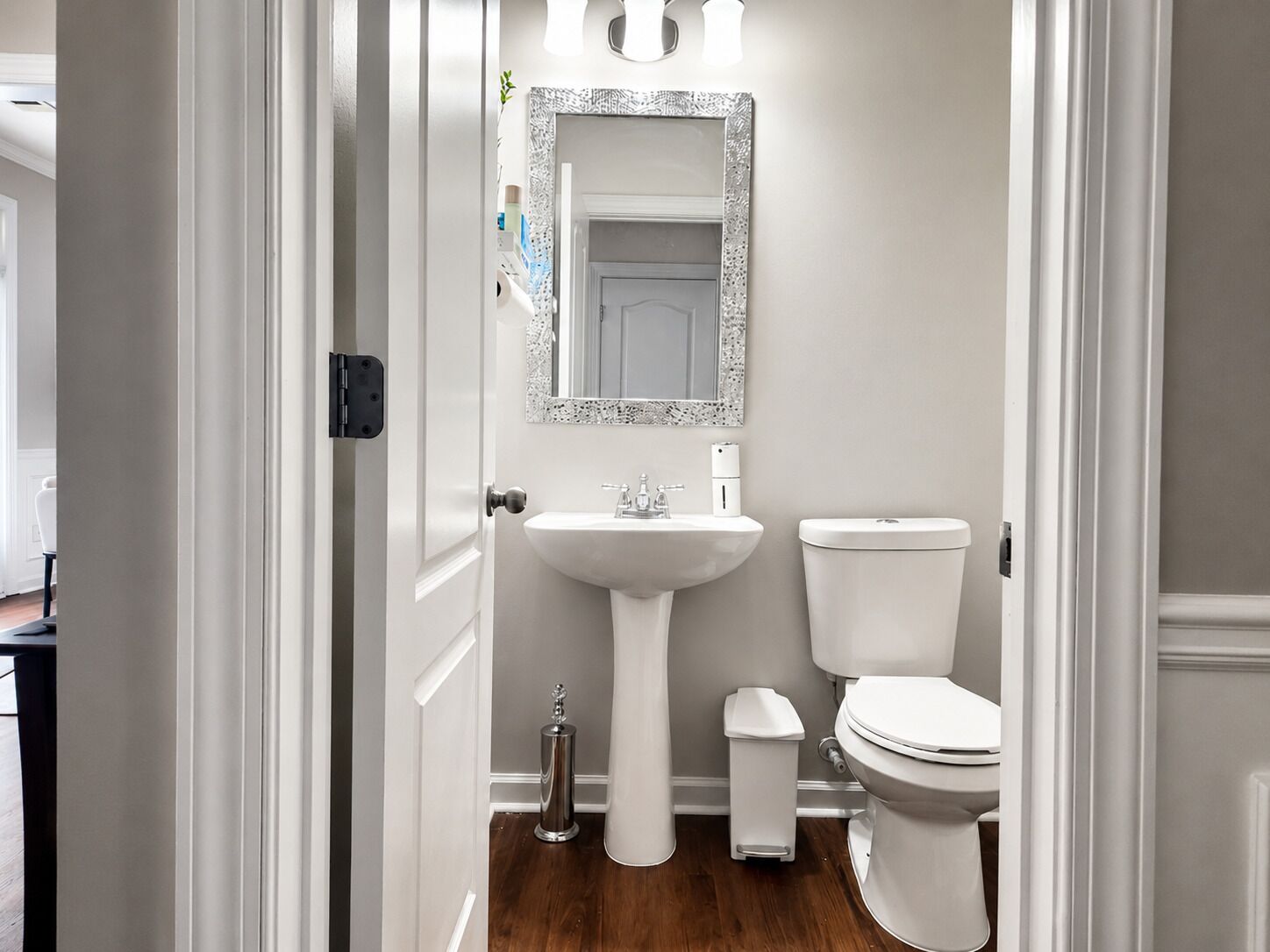 A bathroom with a white sink, toilet, and a trash bin.