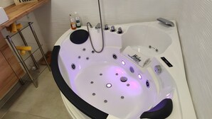 Un baño moderno con una bañera, repisas de vidrio con artículos de aseo y un perchero para toallas.