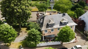 Vista aérea de un edificio residencial con techo inclinado, garaje visible y patio cercado.