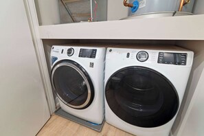 Two front-loading washing machines in a laundry room with a visible water heater above. - Upscale 2BD | Sleeps 4 | Historic Center City Apt (Philadelphia)