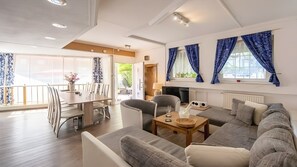 En moderne stue med sofa, stole, spisebord og fjernsyn.
