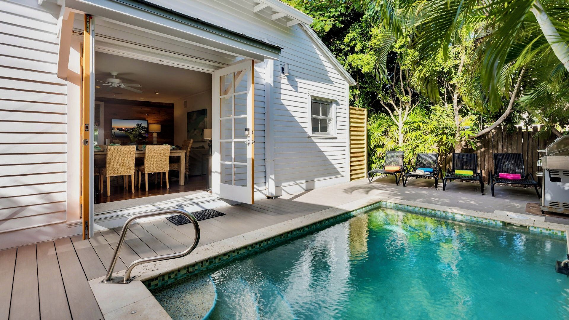 A residential property with a swimming pool, outdoor seating, and a dining area.
