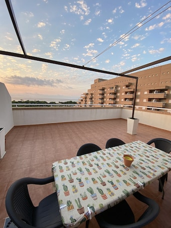 A terrace with a table and chairs, a view of buildings, and a clear sky.. Apartment 'Frontal Jardines Del Mar 2' with Sea View, Wi-Fi and Air Conditioning
